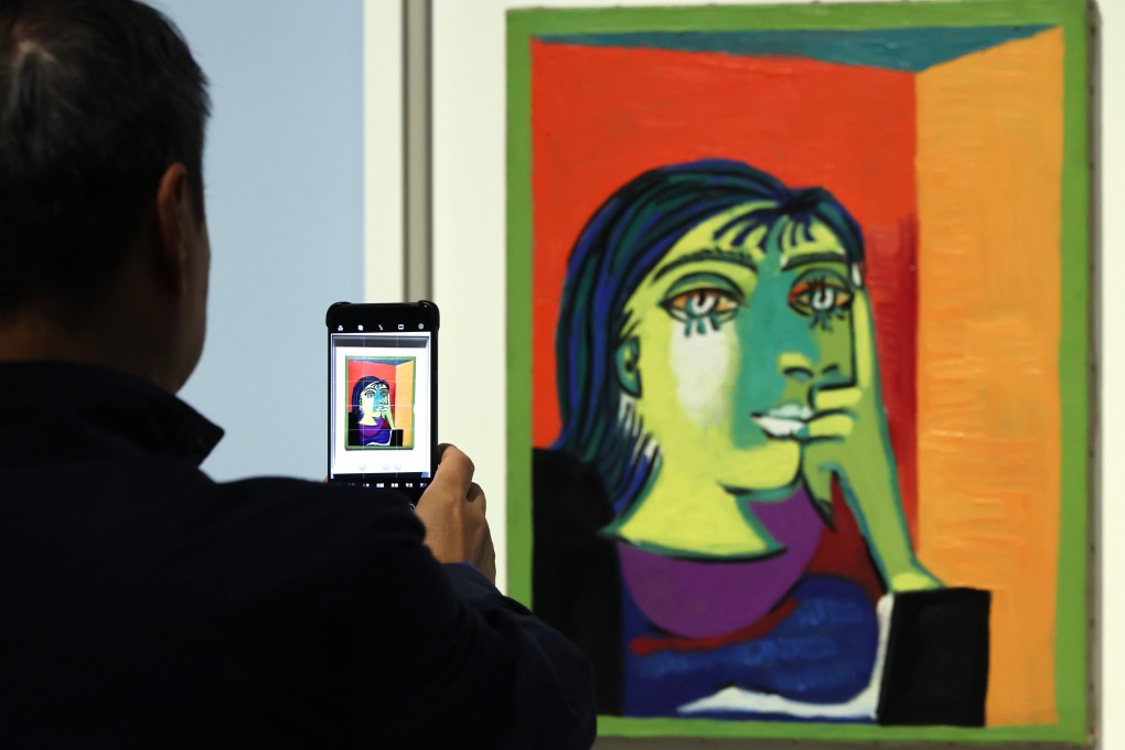 A visitor aims a phone at a portrait at the “Picasso for Asia” exhibition at M+ on March 18. Photo: Nora Tam