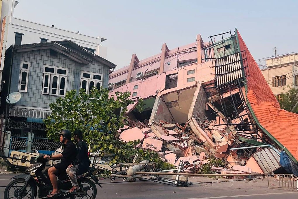 People drive on a motorbike past a collapsed building in Mandalay on March 28 after the earthquake in central Myanmar. Photo: TNS