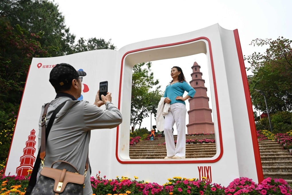 A visitor poses for a photo in front of the red pagoda outside the Tobacco Cultural Centre in Yuxi, in China’s Yunnan province, home to a giant cigarette factory. China is the world’s biggest producer and consumer of tobacco. Photo: AFP