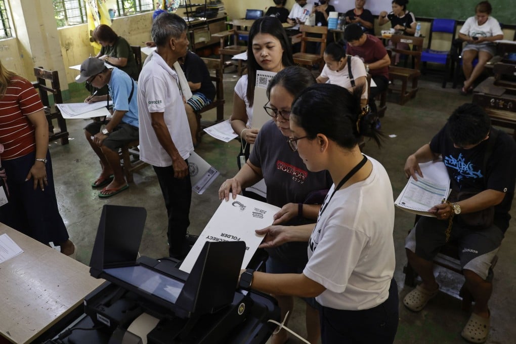 Filipinos feed their ballots into a vote-counting machine at a school used as a voting centre in Quezon City, Metro Manila, Philippines, on Monday. Photo: EPA-EFE