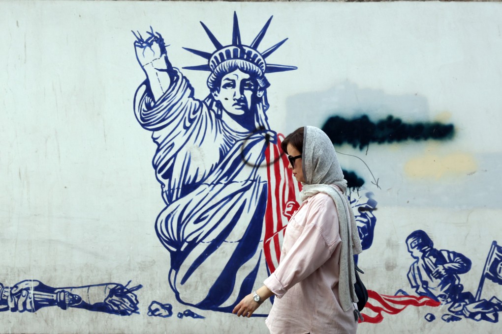 An Iranian woman walks past an anti-US mural near the former US embassy in Tehran. Photo: EPA-EFE