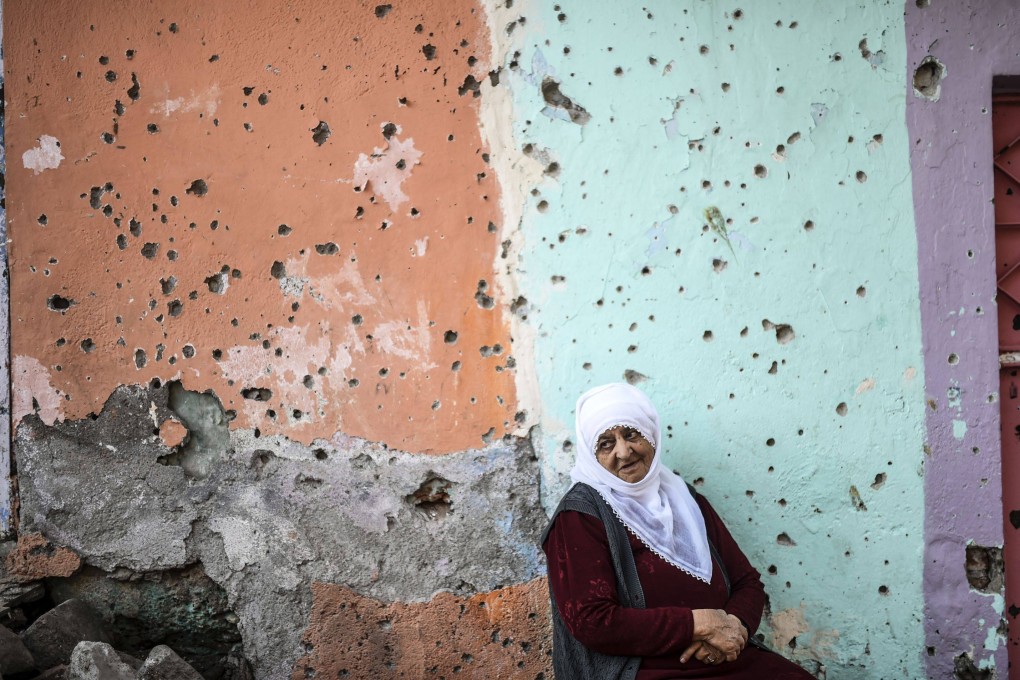 A woman sits in front a bullet-riddled wall damaged during clashes between Turkish troops and Kurdish militants in the district of Sur in Diyarbakir, southeastern Turkey, in 2015. File photo: AFP