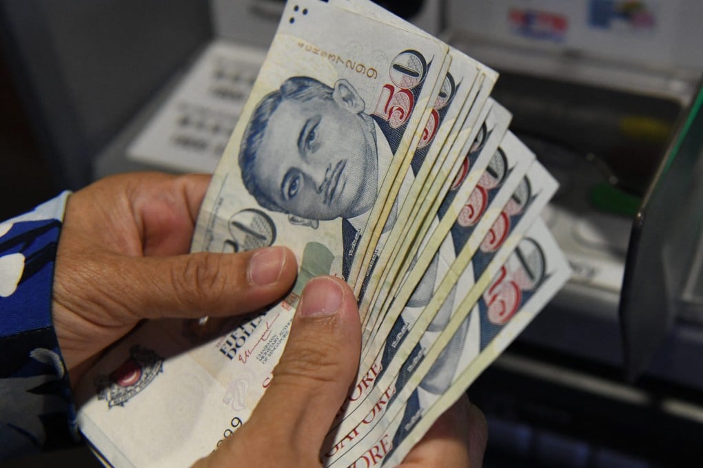 A customer withdraws Singapore dollar notes from an automated teller machine. Photo: AFP
