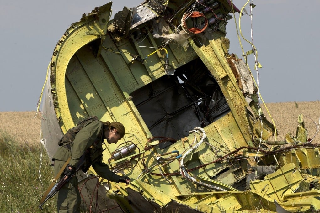 A pro-Russian rebel checks the wreckage of MH17 at the crash site on July 22, 2014. Photo: AP