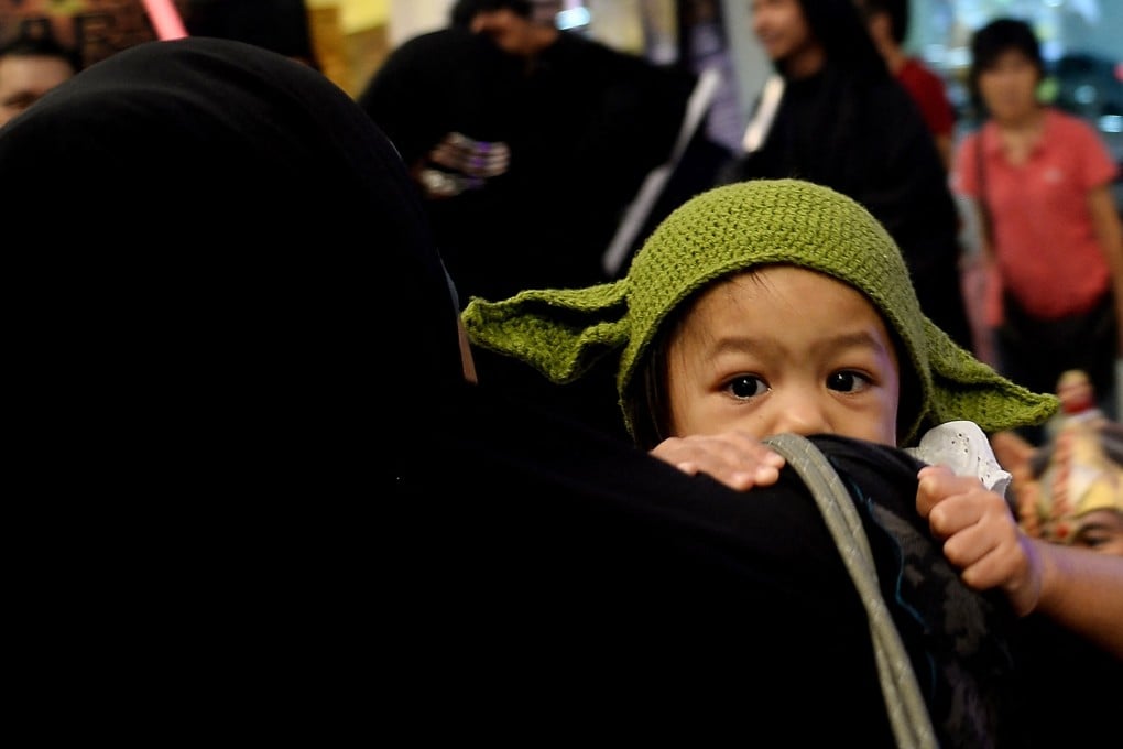 A Malaysian mother carries her child, dressed as baby Yoda, during a Star Wars-themed event in Kuala Lumpur. Photo: AFP