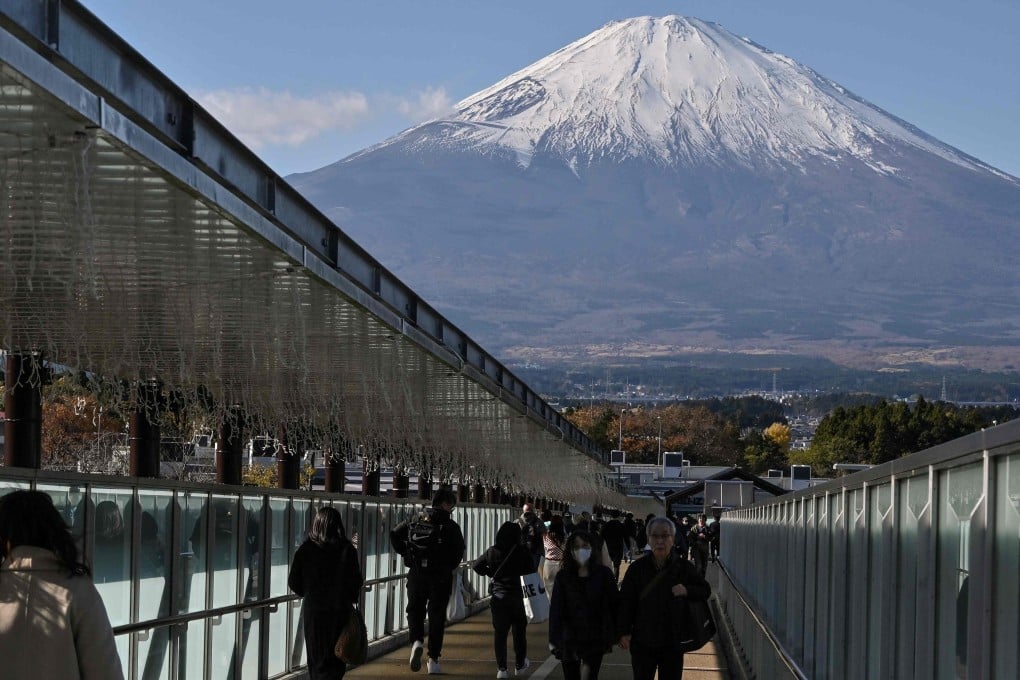 Mount Fuji can be seen in the background as people walk along a bridge connecting stores at a popular outlet shopping centre in the city of Gotemba, Shizuoka prefecture. Photo: AFP