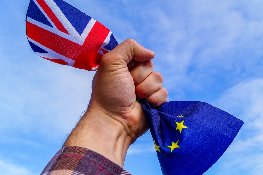A male hand holds in his fist the flags of England and the European Union. Photo: Shutterstock