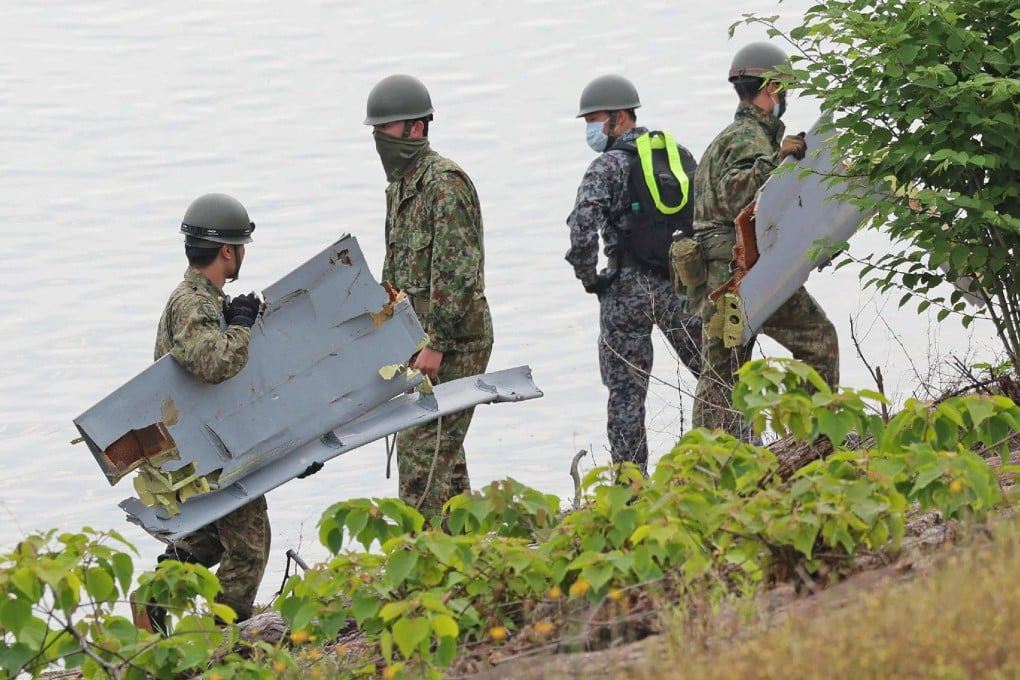 Japan Self-Defence Forces personnel carry debris believed to be part of the crashed aircraft at Lake Iruka reservoir, Aichi prefecture, on May 15. Photo: Jiji Press / AFP