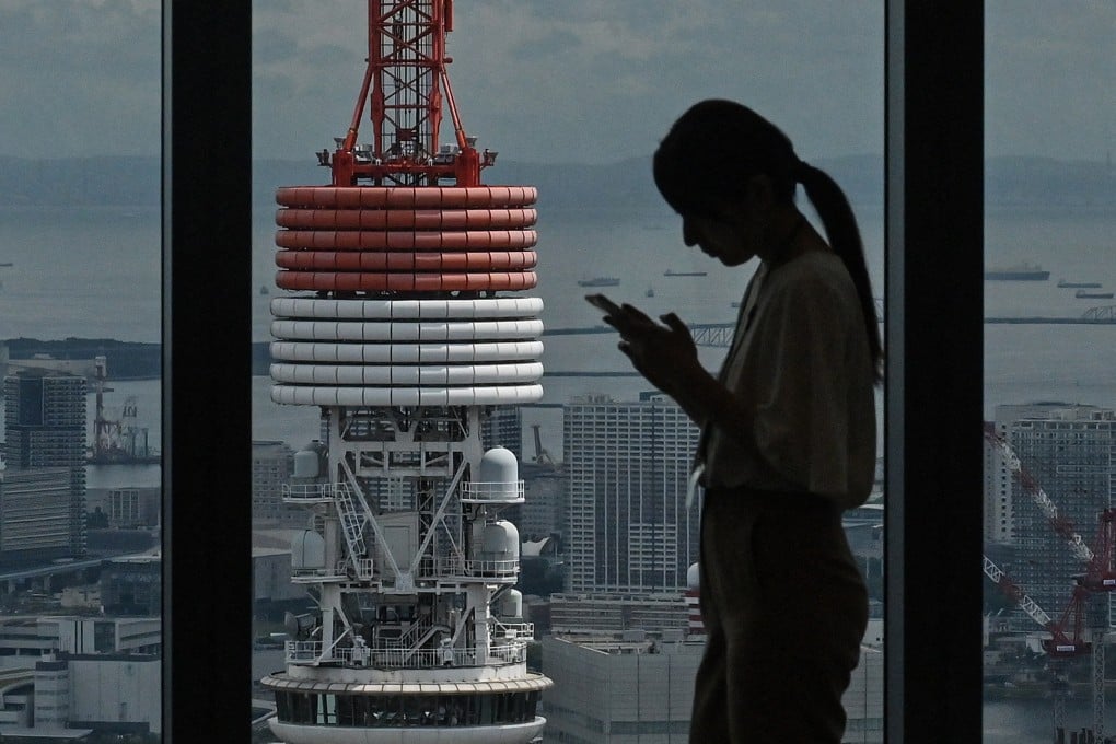 A woman checks her phone near Tokyo Tower in central Tokyo. Japanese police have warned that romance scammers are increasingly using dating apps to target vulnerable individuals. Photo: AFP
