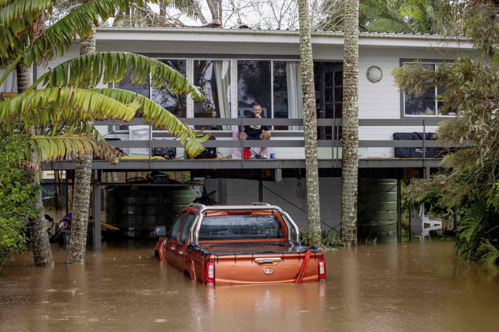 A man sits on the balcony of a house surrounded by floodwaters in Port Macquarie, north of Sydney, Australia, on Friday. Photo: via AP