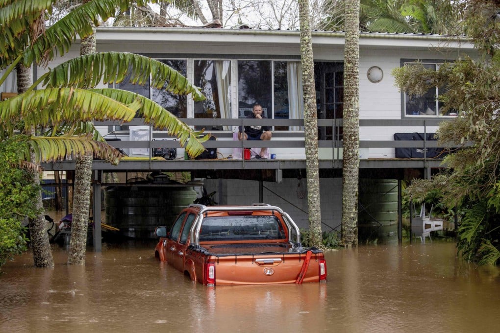 A man sits on the balcony of a house surrounded by floodwaters in Port Macquarie, north of Sydney, Australia, on Friday. Photo: via AP