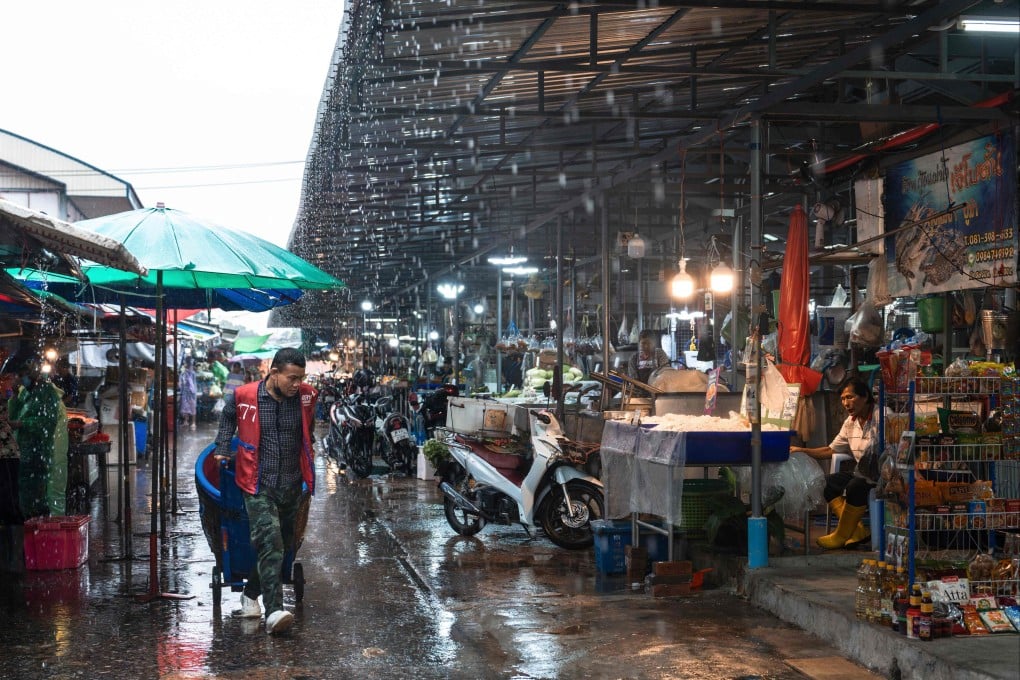 A man pushes a barrel on a metal cart at Khlong Toei Market during a rain storm in Bangkok on May 14. In Thailand, the AI Nowcast system is forecasting rainfall in Bangkok three hours ahead of time, enhancing the city’s flood preparedness. Photo: AFP