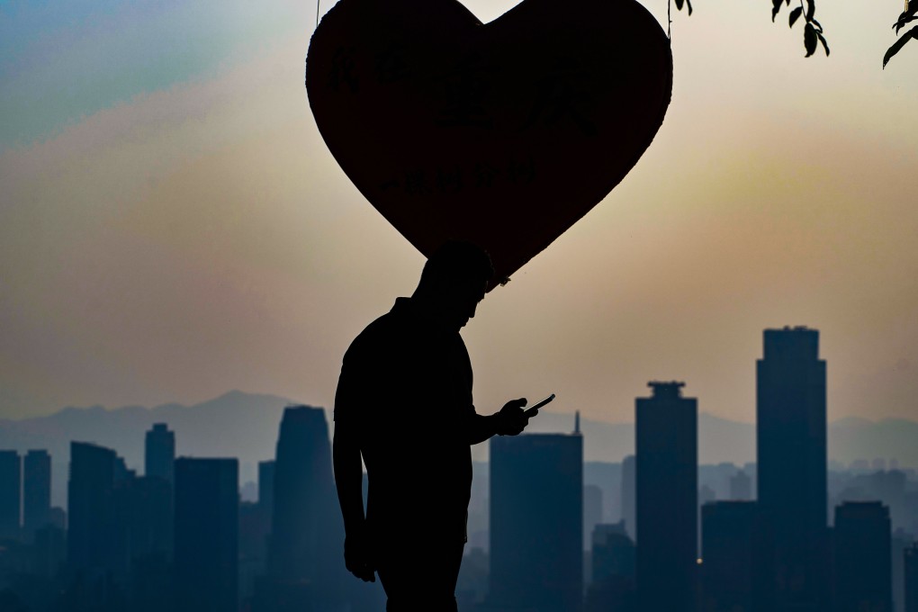 A man looks at his phone near a heart-shaped display in southwest China’s Chongqing on Monday. The country’s top spy agency has warned citizens to be wary of overseas friends who were “overly eager” in pursuit of romance. Photo: AP