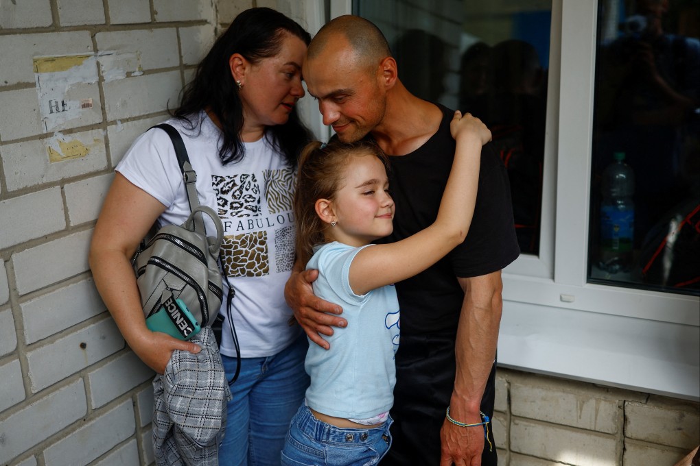 Ukrainian prisoner of war Viktor embraces his daughter Milana and wife Iryna as he returns after a prisoner swap in an undisclosed location in Ukraine on Sunday. Photo: Reuters