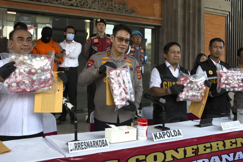 Authorities hold a news conference as an Australian man (second left in the background) arrested for smuggling cocaine stands at the police headquarters in Bali on Monday. Photo: AP