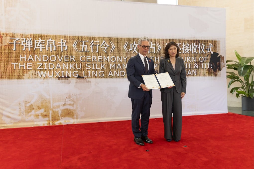 Chase F. Robinson (left), director of the Smithsonian’s National Museum of Asian Art, receives a certificate of appreciation from Zhu Ye, deputy director-general of Office for the Recovery and Restitution of Lost Cultural Property, National Cultural Heritage Administration of China, during a handover ceremony of the ancient Zidanku Silk Manuscripts in Washington on May 16. Photo: Xinhua