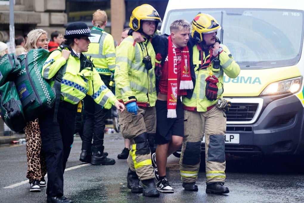 Police and emergency personnel help a man after a car collided with Liverpool fans. Photo: PA via AP