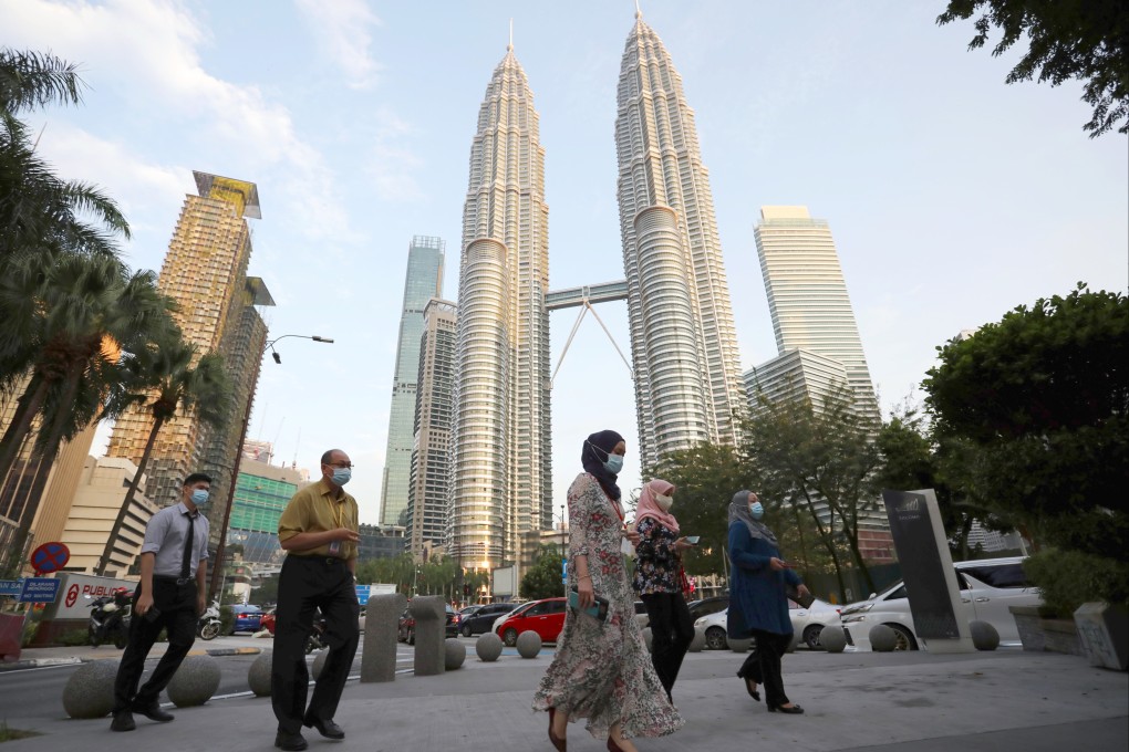 People cross a street in front of Petronas Twin Towers in Kuala Lumpur, Malaysia on November 5, 2020. Photo: Reuters