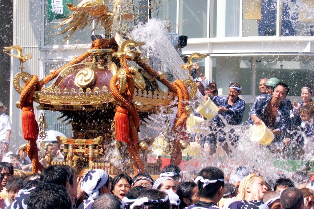 Spectators throw buckets of water onto a portable shrine during the Fukagawa summer festival in Tokyo on August 15, 1999, a ritual meant to purify and cool participants amid the summer heat. Photo: AFP