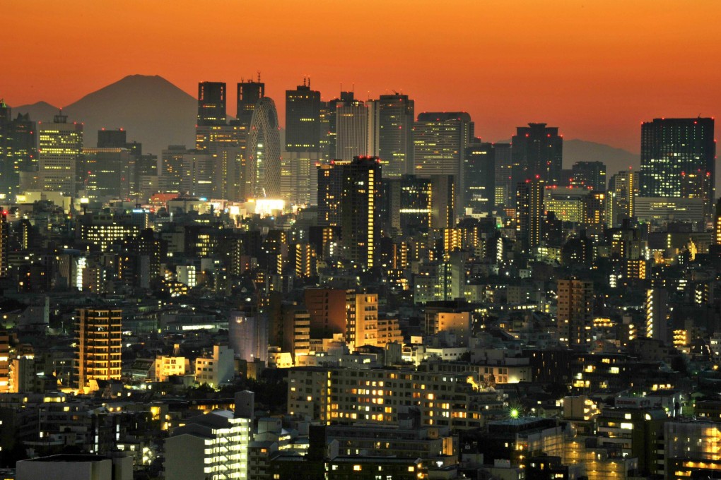 Japan’s highest mountain Mount Fuji rises up behind the skyscrapers dotting the skyline of the Shinjuku area of Tokyo at sunset. Photo: AFP