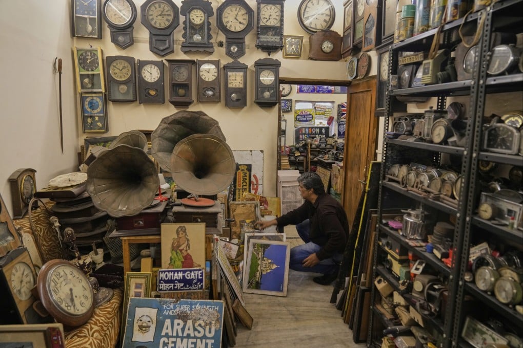 Indian anthropologist Aditya Vij crouches near old clocks, pictures and gramophones at his New Delhi home museum of vintage items. Photo: AP