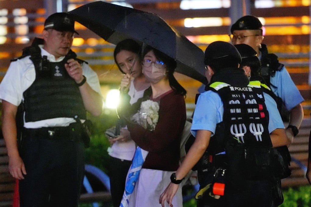 A youngster in school uniform and holding a bouquet is stopped by police. Photo: Elson Li