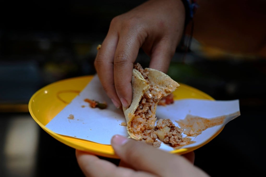 A woman eats a taco at a street food stall in the Roma neighbourhood in Mexico City in May 8. The latest acronym popular among traders and investors is Taco, short for “Trump always chickens out”, a reference to US President Donald Trump’s habit of making concessions after initially talking tough on trade and tariffs. Photo: AFP