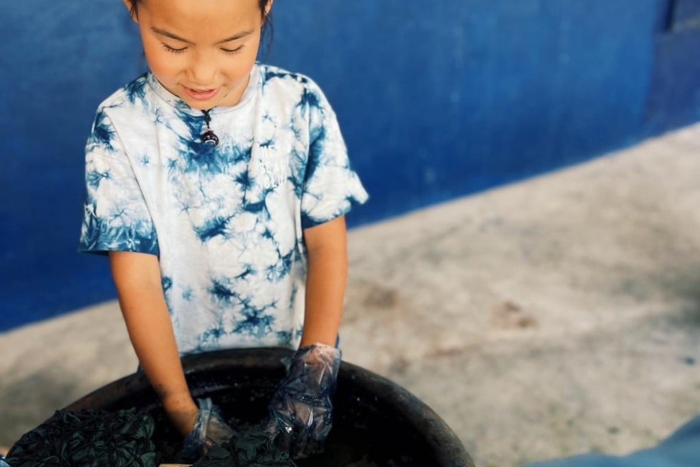Emilia Li, eight, from Hong Kong, dyes a T-shirt for her Shek O Beach Club tie-dye fashion brand at a workshop in Guizhou province, southwest China, where she is helped by women of the Dong ethnic minority. Photo: Shek O Beach Club
