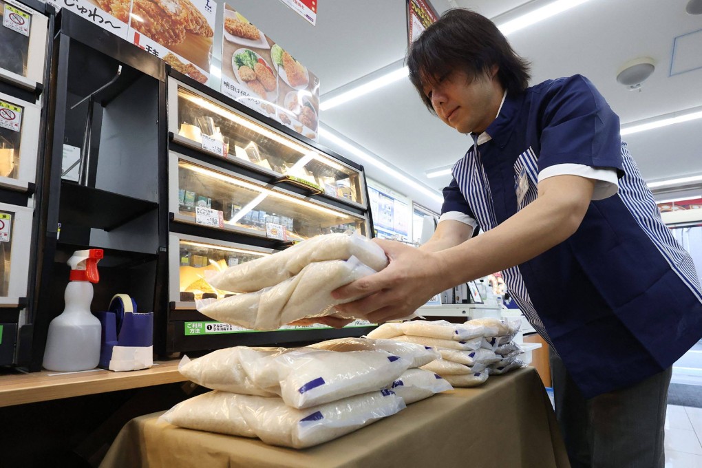 A staff member displays bags of the government-stockpiled rice at a convenience store in Tokyo on June 5. Photo by JIJI PRESS/AFP