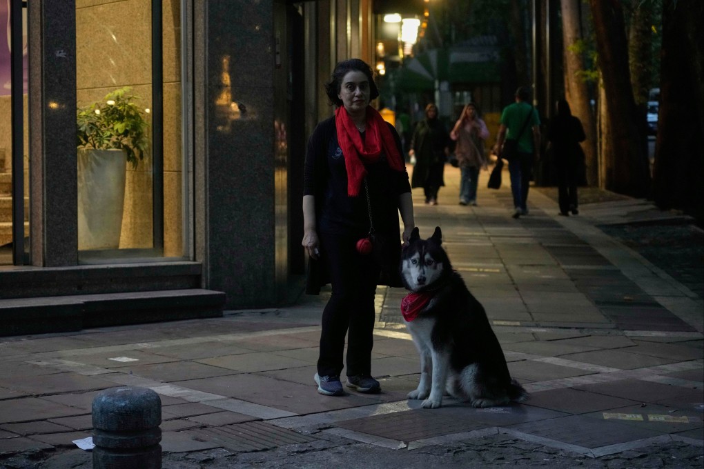 A woman stands with her dog, Lucifer, on a sidewalk in northern Tehran, Iran, on Monday. Photo: AP