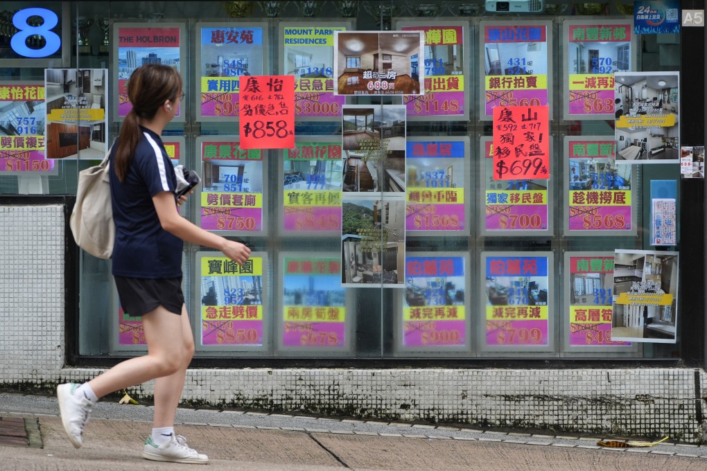A woman looks at slashed property prices advertised at a real estate agency in Tai Koo on July 29, 2024. Photo: Eugene Lee