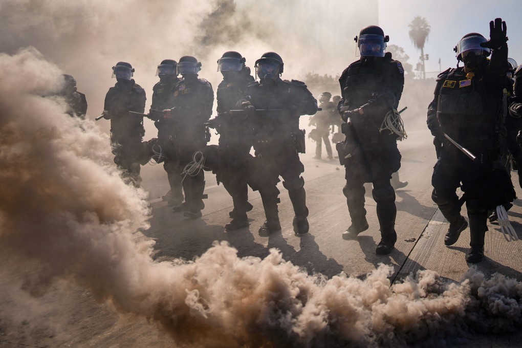 Police are seen through smoke on a motorway as protests rock downtown Los Angeles on June 8. Photo: AP