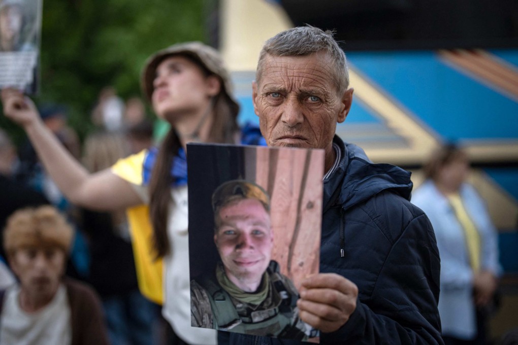 A man holds a portrait of his missing or captured son during the arrival of freed injured and severely wounded Ukrainian POWs on Tuesday. Photo: AFP