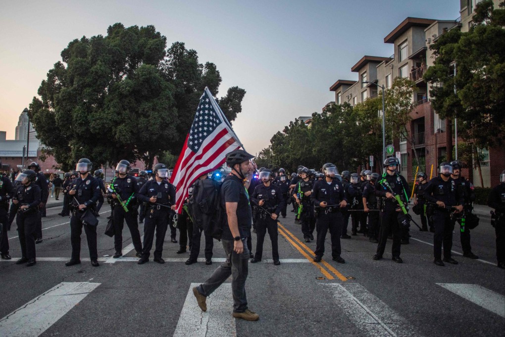 A man with an American flag in front of the Los Angeles Metro Police, as they try to disperse a protest at the Little Tokyo neighbourhood against immigration raids, on June 9. Photo: AFP