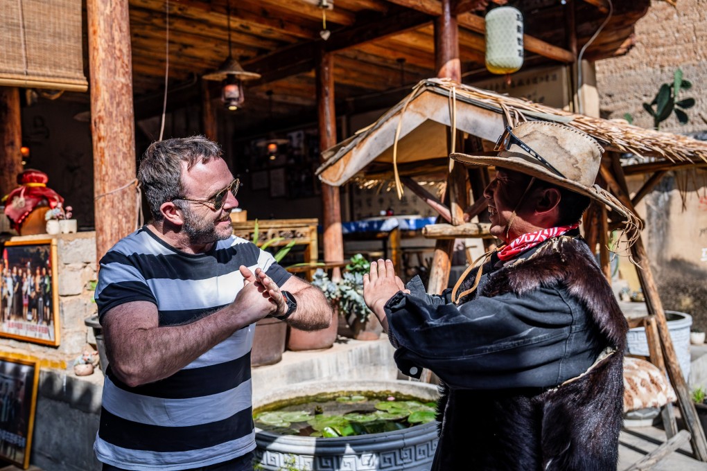 Yang Siyun (right), a descendant of local horse train operators, bids farewell to a foreign tourist at Sideng village in southwest China’s Yunnan Province, on April 19. Photo: Xinhua