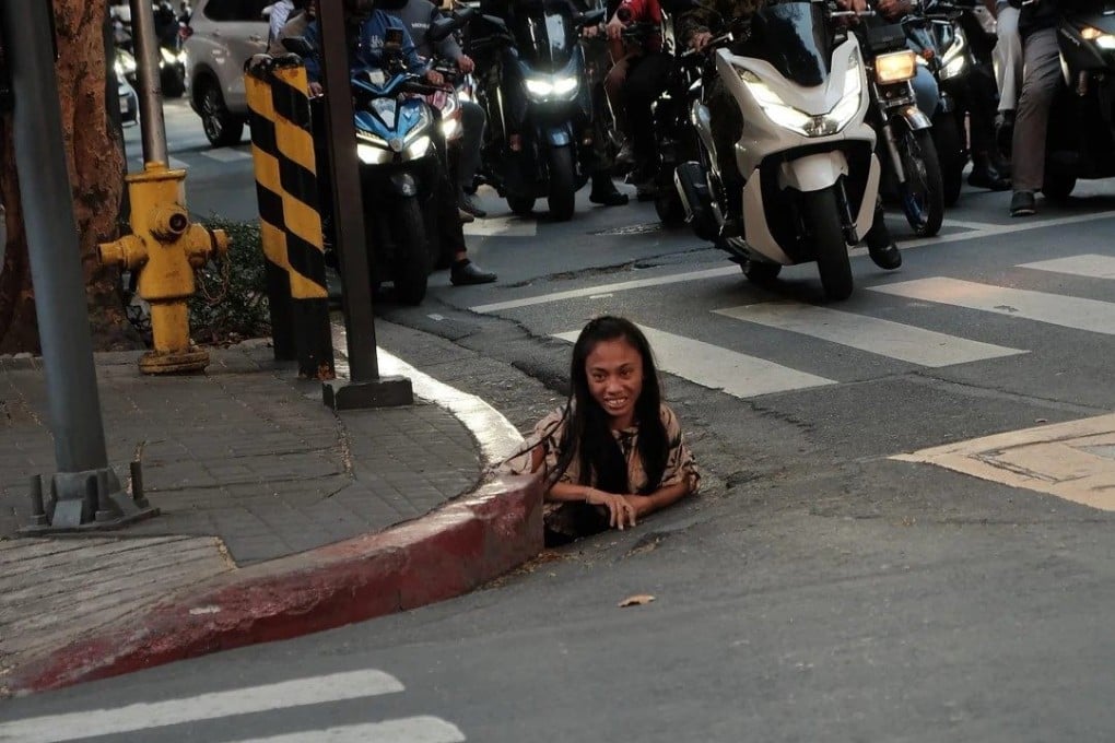 A woman is photographed emerging from a drainage hole along a street in Makati City in the Philippines. Photo: William Roberts