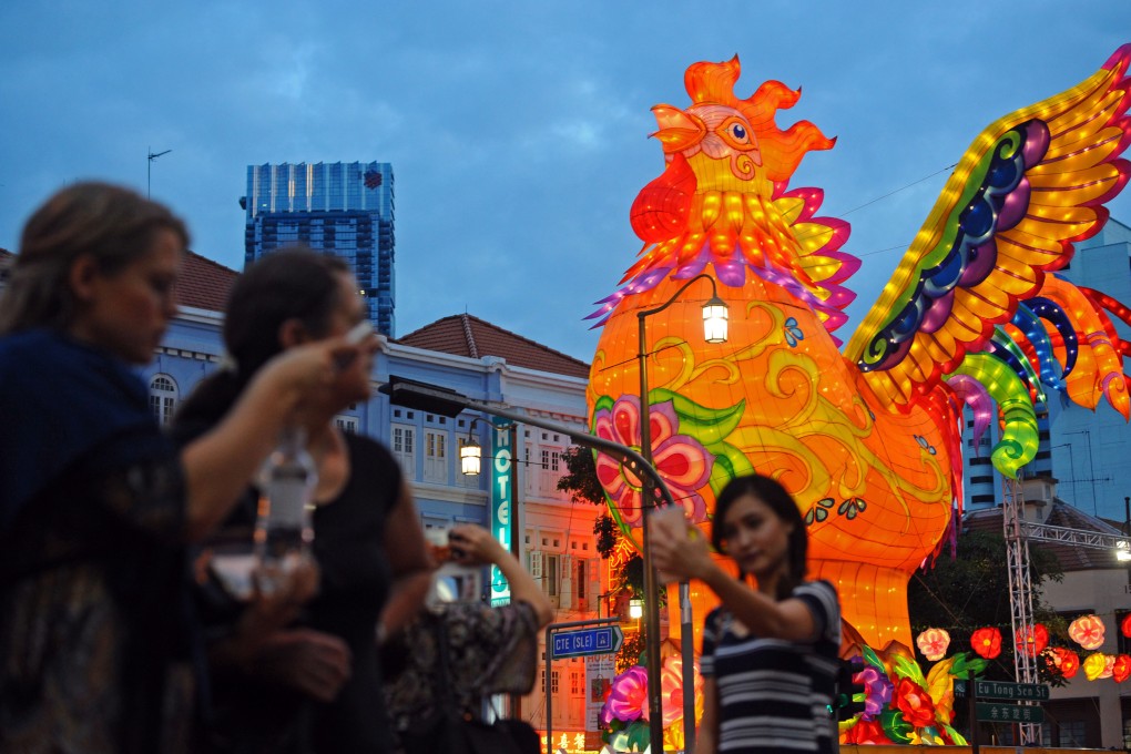 People take photos in front of a giant golden rooster lantern in Singapore’s Chinatown in preparation for the upcoming Lunar New Year on January 4, 2017. In recent decades the area has become a tourist hub where boutiques stand beside old tea houses and Buddhist temples Photo: Xinhua