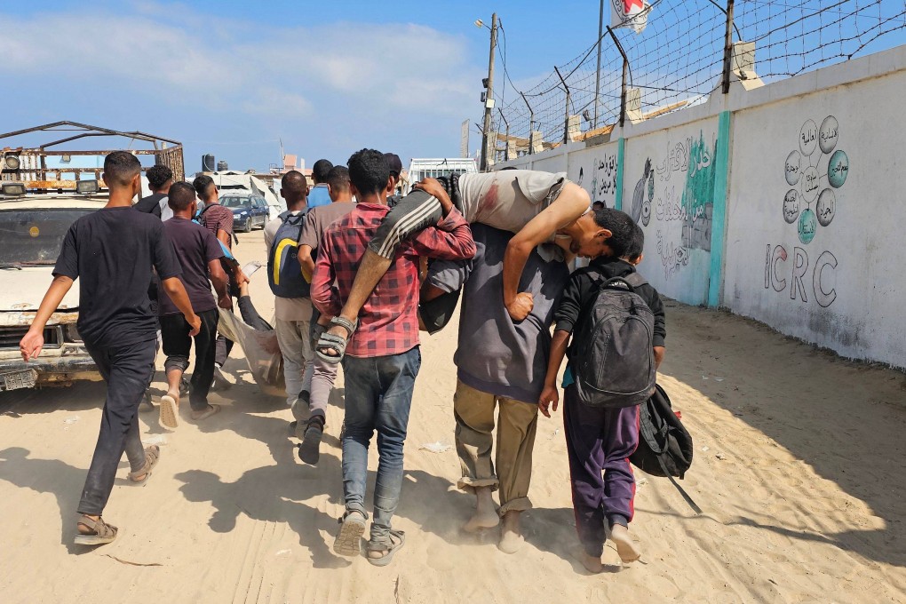 Palestinians carry a wounded young man, injured as he was queuing for aid, towards a hospital in Rafah in the southern Gaza Strip on Monday. Photo: AFP