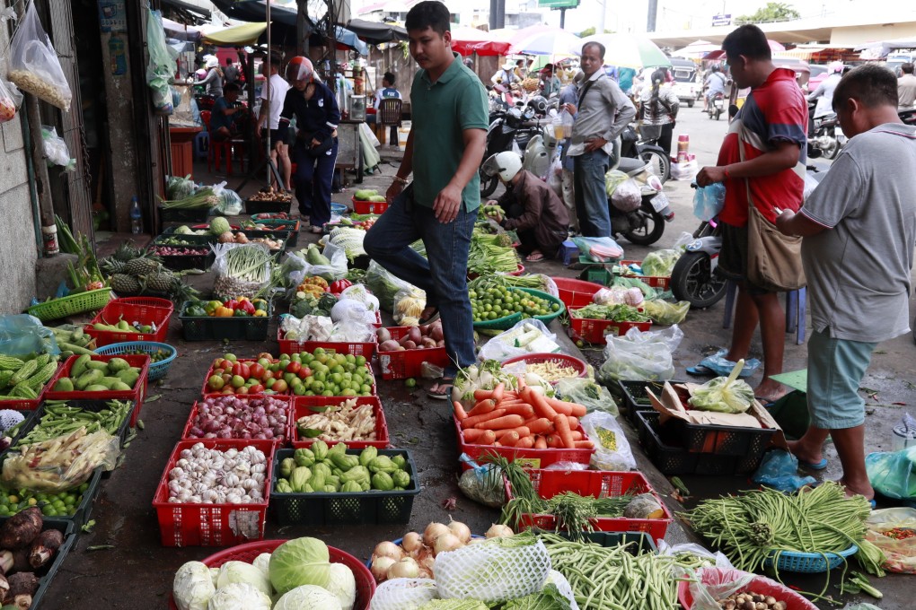 People buy vegetables at a market in Phnom Penh, Cambodia, earlier this month. Photo: EPA-EFE