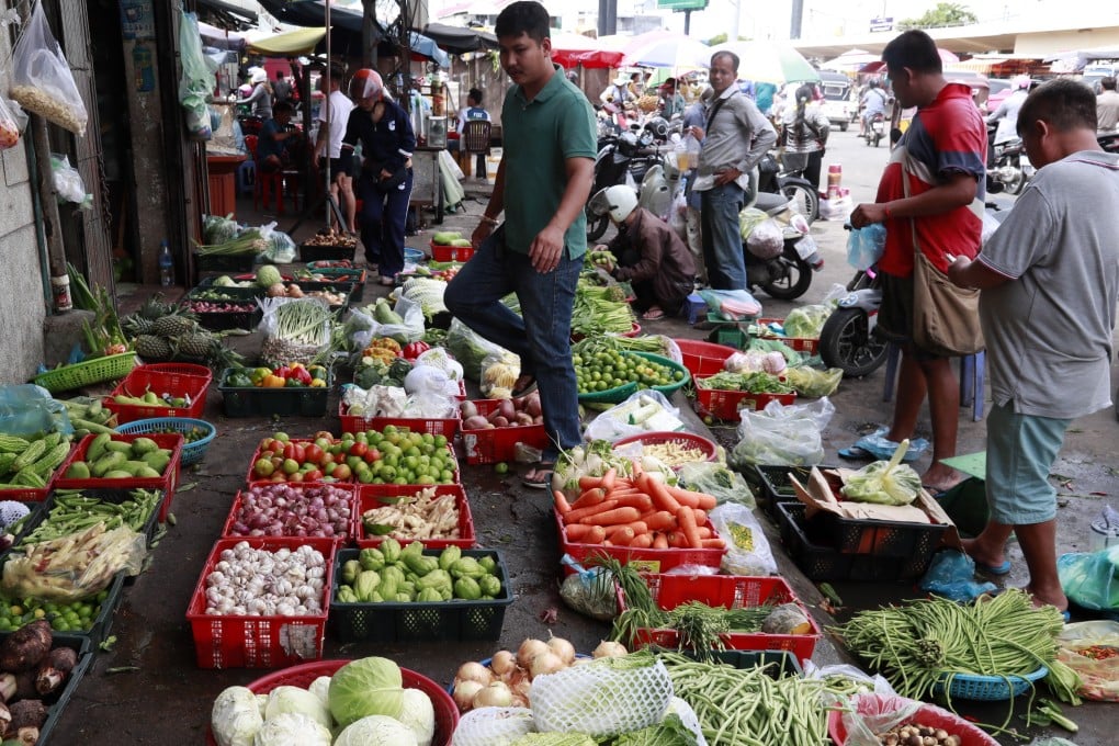 People buy vegetables at a market in Phnom Penh, Cambodia, earlier this month. Photo: EPA-EFE
