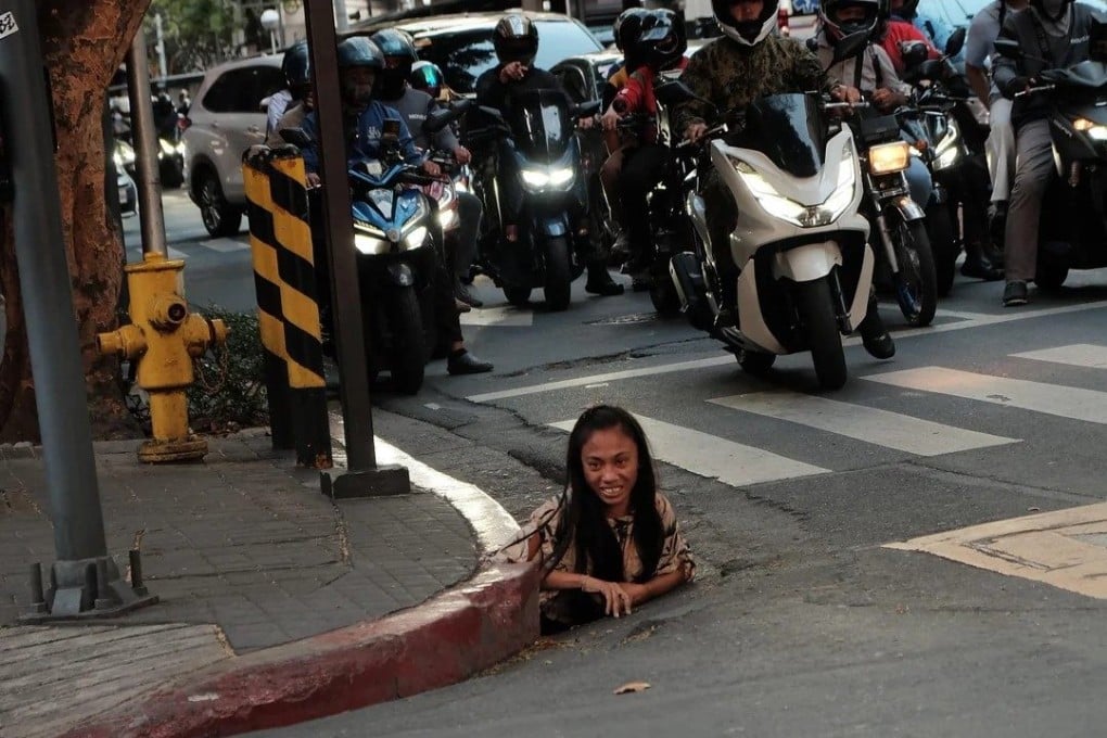 A woman is photographed emerging from a drainage hole along a street in Makati City in the Philippines. Photo: William Roberts