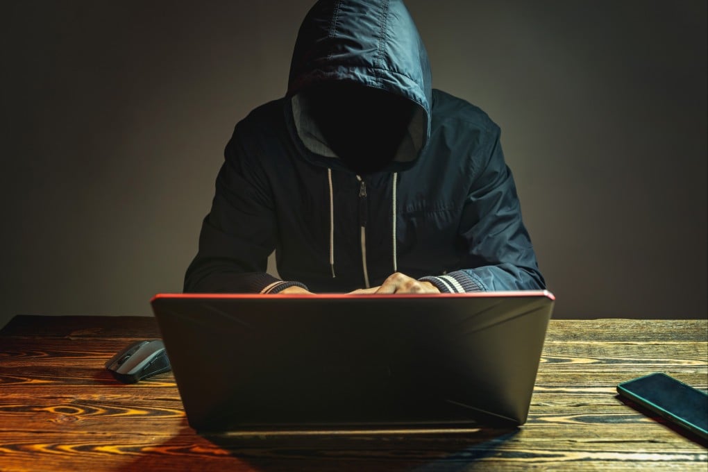 A hooded figure types on a laptop in a dark room, symbolising the anonymous spread of extremist content online. Photo: Shutterstock