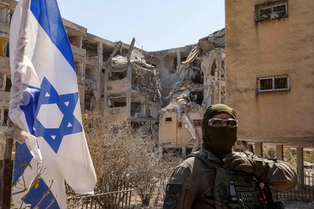 A masked Israeli policeman stands guard outside a building that was hit by an Iranian missile in Israel’s central city of Holon on Thursday. Photo: AFP