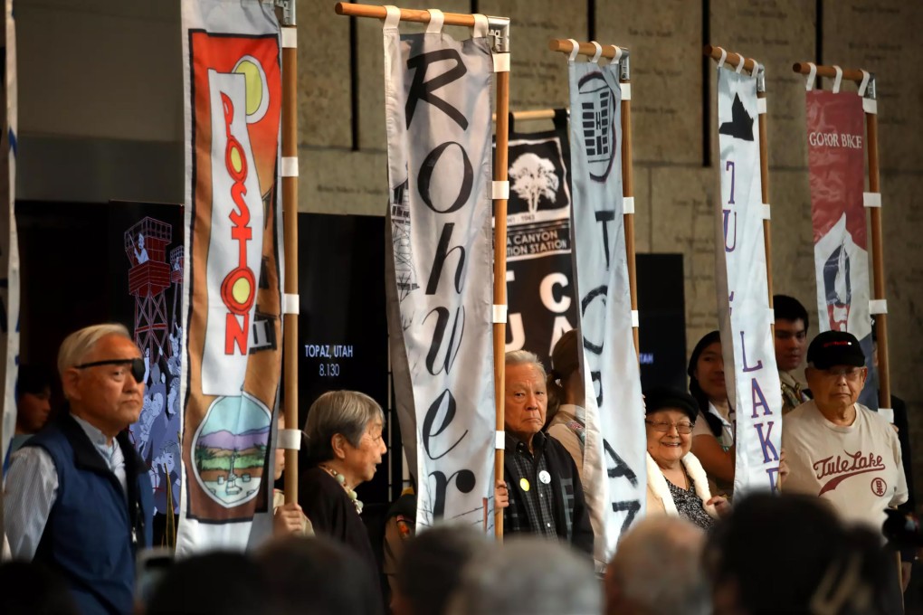 Visitors at the Japanese American National Museum in Los Angeles stand beside flags representing World War II incarceration camps on February 17, 2024, during a commemoration of Executive Order 9066 – the 1942 directive that authorised the forced relocation of Japanese Americans. Some participants had been detained at the camps or had family members who were. Photo: TNS