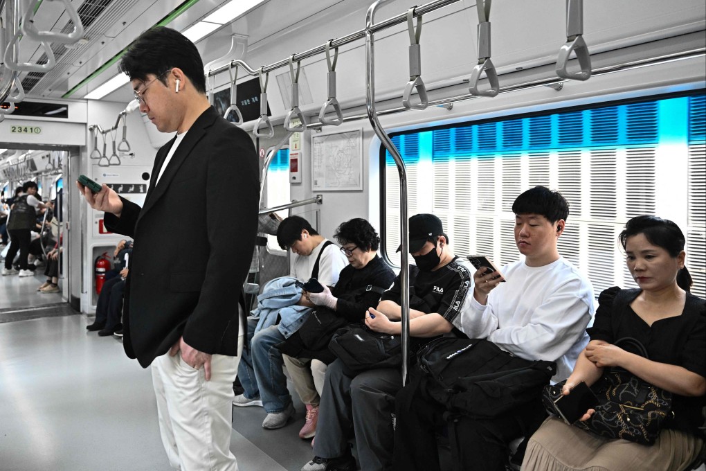 Commuters use their phones while travelling in a metro train in Seoul on May 28. Thirteen maintenance workers with Seoul Metro have so far been diagnosed with blood cancer. Photo: AFP
