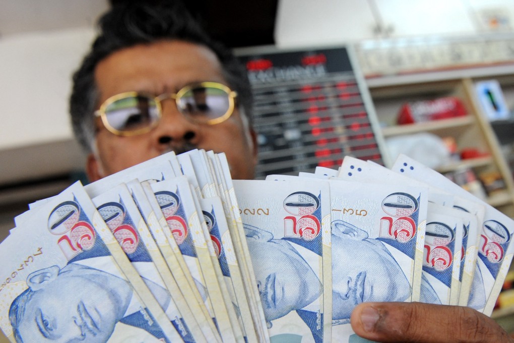 A dealer displays Singapore dollar notes at a money changer in Singapore. Photo: AFP