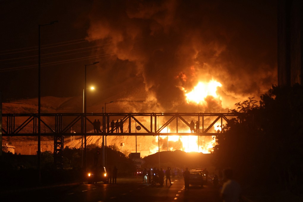 Pedestrians and drivers watch the Sharan Oil depot on fire following Israeli strikes, in Tehran, Iran, on Sunday. Photo: Reuters