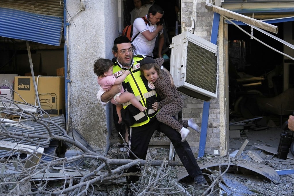 A rescuer evacuates two children from the site where a missile launched from Iran struck in Haifa, Israel, on Sunday. Photo: AP