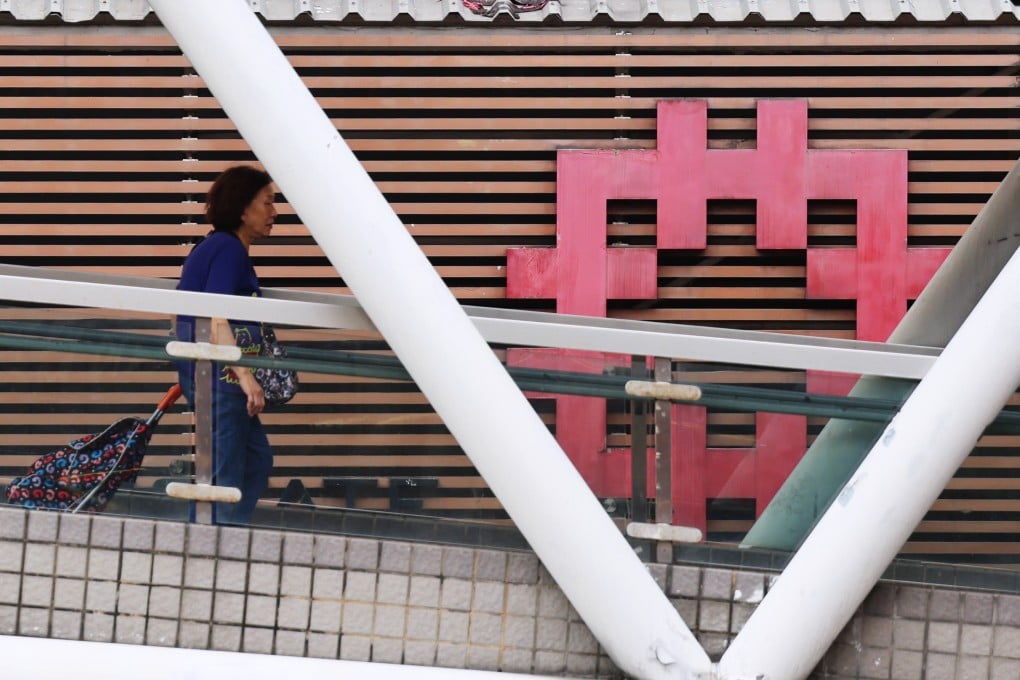 A woman walks past a building with a Hong Kong Housing Authority logo. The Housing Authority has said that the contractor’s performance on three projects is “far below” contract requirements. Photo: Jelly Tse