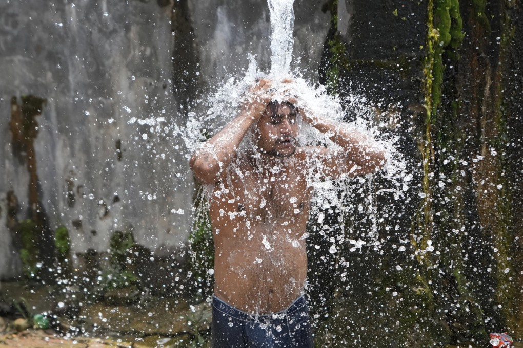 A man in Jammu, India, bathes from a roadside water tap on June 15 to cool himself off on a hot summer day. Photo: AP